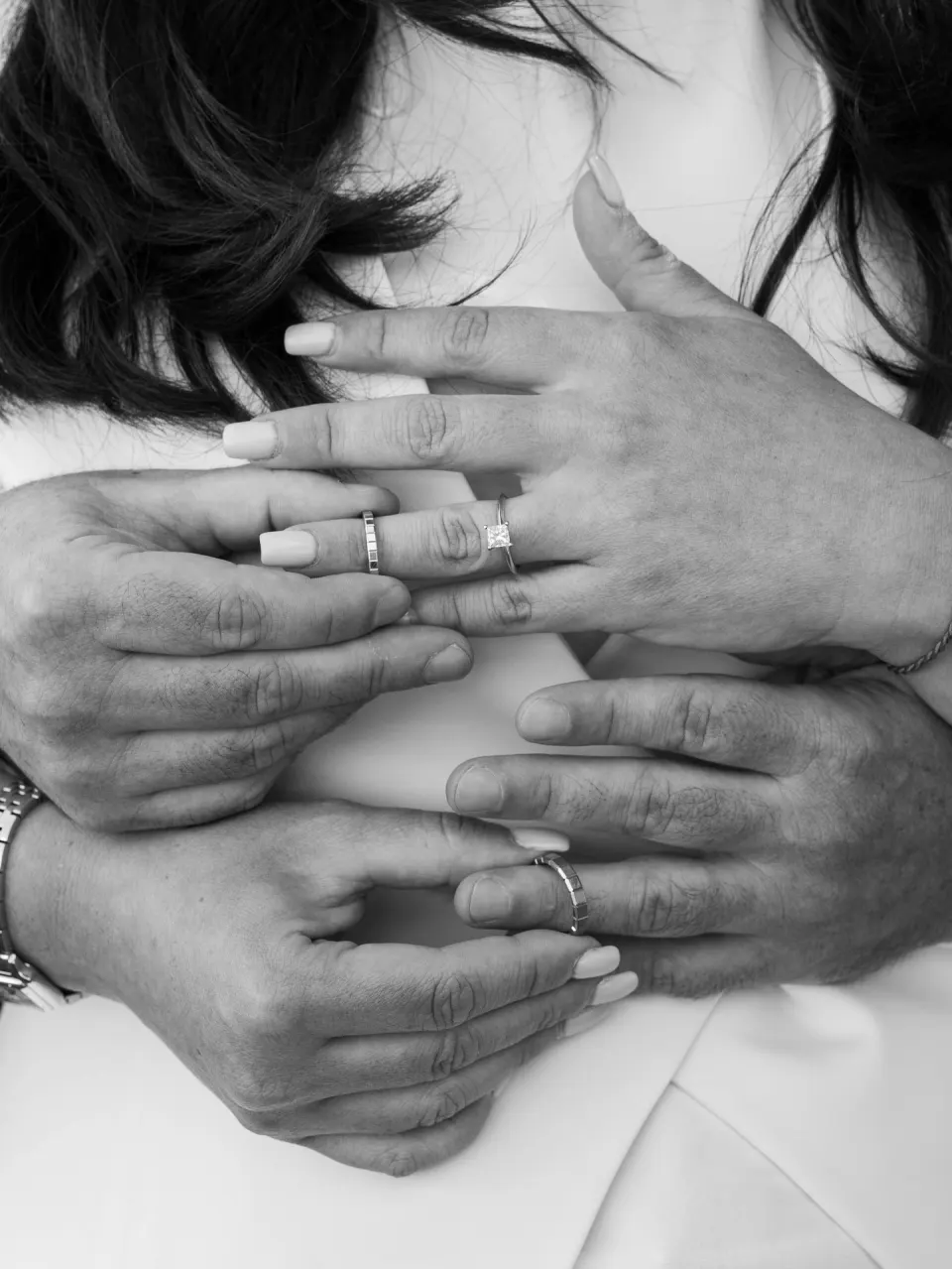 Wedding rings and hands of newlyweds, black and white detail